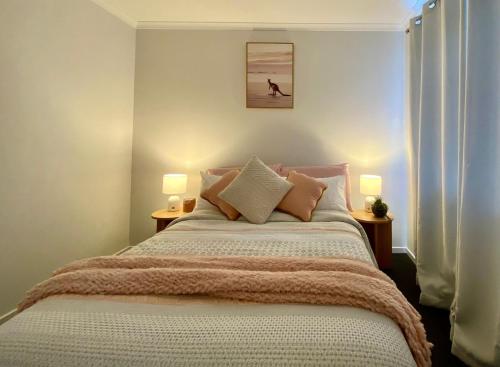 a bedroom with a large bed with two lamps at Bella's Beach House in Venus Bay