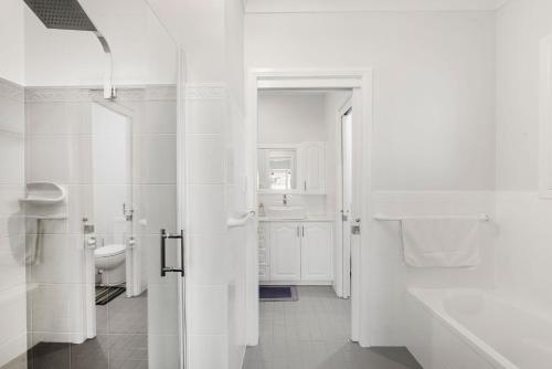 a white bathroom with a toilet and a sink at Dolphin Cove - Pet Friendly with Fireplace in Callala Bay