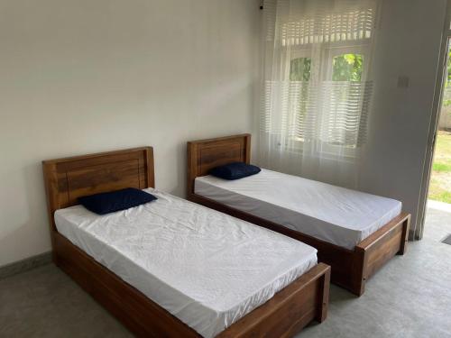 two twin beds in a room with a window at N28 Negombo in Negombo
