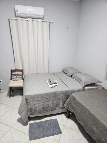 a bedroom with two beds and a chair at Terraço sol e lua in Belém
