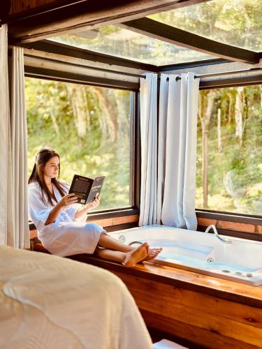 a woman is sitting in a window reading a book at Maria Rita dos Canyons in Praia Grande