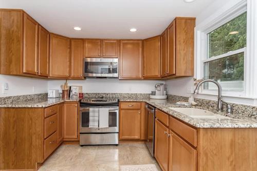 eine Küche mit Holzschränken und Geräten aus Edelstahl in der Unterkunft 3 bed 2 bath-Walk to Jack Trice Stadium in Ames