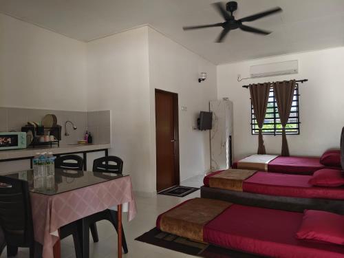 a bedroom with two beds and a table and a ceiling fan at Sofia roomstay 2 in Kampong Beris Meraga