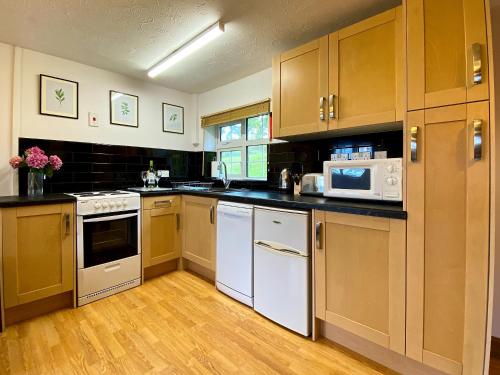 a kitchen with white appliances and wooden cabinets at Dabinett in Ledbury