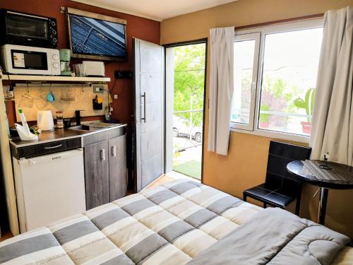 a bedroom with a bed and a kitchen with a window at Microbed in Cipolletti