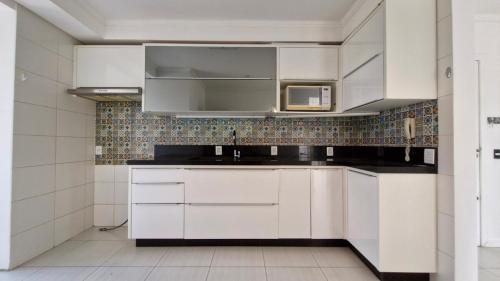 a kitchen with white cabinets and a microwave at Apartamento 3 quartos prox passeio Pedra Branca in Palhoça