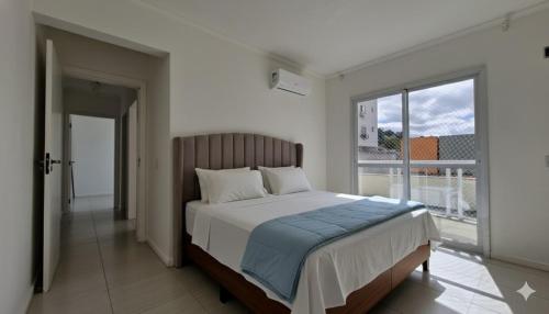 a bedroom with a bed and a large window at Apartamento 3 quartos prox passeio Pedra Branca in Palhoça
