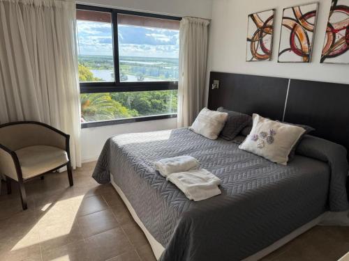 a bedroom with a bed with a chair and a window at Apart -Hotel Rio Manso "Habitación 22" in Victoria