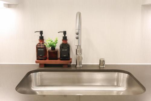 a stainless steel sink with two bottles on a counter at Resort-Style APT with Pool, Gym & Parking 10min to Disneyland in Tustin