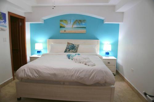 a bedroom with a large white bed with blue walls at Tranquil Oceanside: Pools & Direct Beach Access in Lowlands