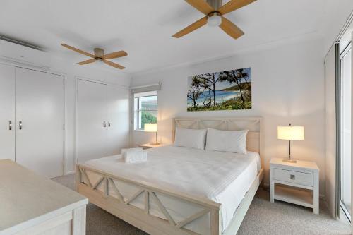 Un dormitorio blanco con una cama y un ventilador de techo. en Pandanus Coolum Beach, en Coolum Beach