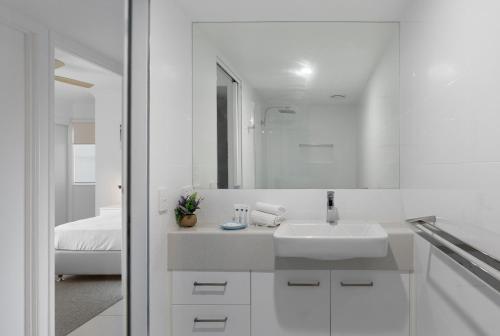 Un baño blanco con lavabo y espejo. en Pandanus Coolum Beach, en Coolum Beach