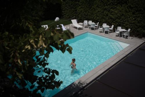 a person in a swimming pool with chairs and a ball at Isola Verde Resort in Castiglione del Lago