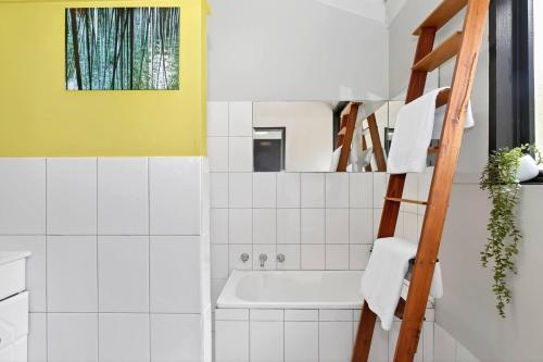 ein Badezimmer mit einer weißen Badewanne und einer gelben Wand in der Unterkunft Treetop Sanctuary - Serene Cottage near Mount Lofty in Upper Sturt