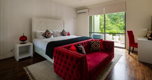 a bedroom with a large bed and a red couch at Villa 98 in Malabe