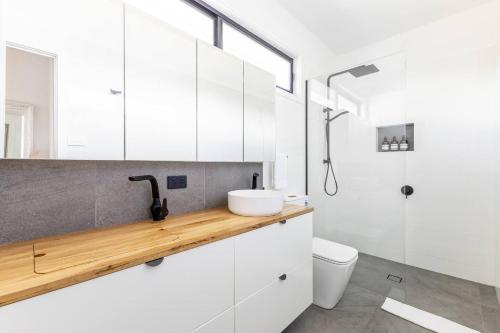a bathroom with white cabinets and a sink and a shower at Oaklight Haven - Minutes to Geelong Waterfront & CBD in Hamlyn Heights