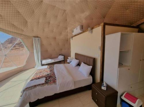 a bedroom with a bed and a large window at Rum Aranda camp & Jeep Tour in Wadi Rum