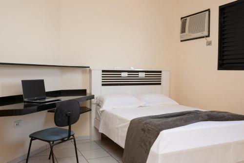 a bedroom with a bed and a desk with a laptop at Bela Casa Stella Maris - Casa de Carrara 01 in Andradina