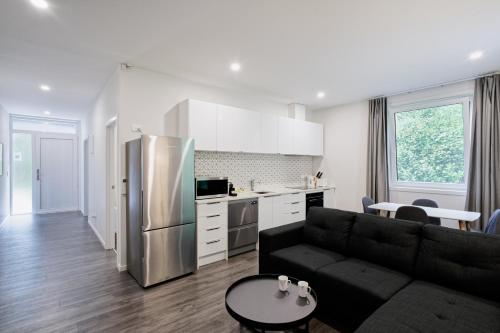 een woonkamer met een zwarte bank en een keuken bij Recently Renovated Central Apartment in Dunedin