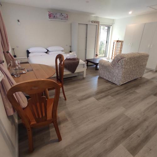 a room with a bed and a table and a chair at Quiet 40m Studio - Kitchen, Washer, AC, Work Desk in Auckland