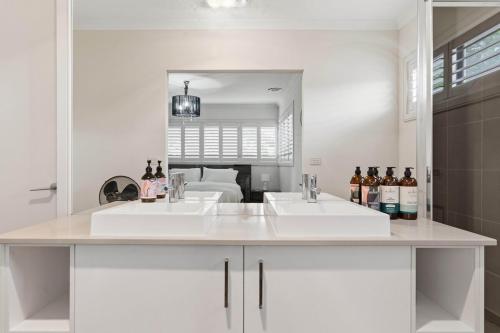 a white bathroom with two sinks and a mirror at Modern Family Retreat in Prime Williams Landing in Williams Landing