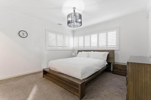 a white bedroom with a bed and a chandelier at Modern Family Retreat in Prime Williams Landing in Williams Landing