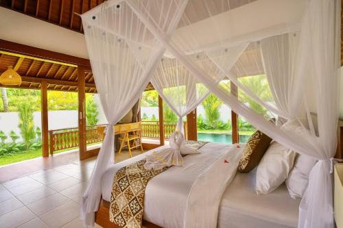 een slaapkamer met een groot bed met witte gordijnen bij Ubud Forest Villa with Private Pool and Kitchen in Payangan