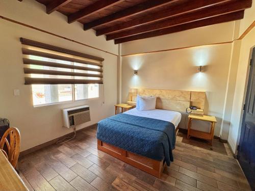 a bedroom with a bed with a blue blanket and a window at Hotel Paris in Tijuana