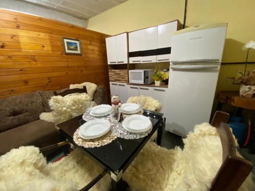 a kitchen with a table with white plates and a refrigerator at kitinet centro econômico in Santo Antônio do Pinhal