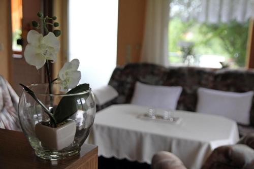 a living room with a table with a vase with flowers at Ferienhaus Am Weiher in Waltershausen