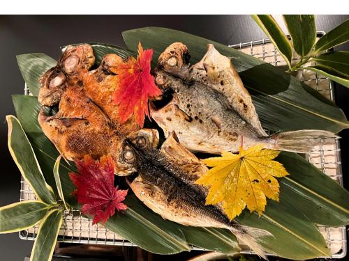 two dried fish sitting on a rack with autumn leaves at 箱根薫風 in Hakone