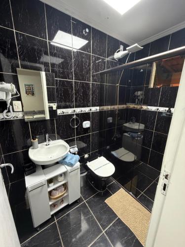 a black tiled bathroom with a sink and a toilet at Loft BC ESTÚDIO Centro in Balneário Camboriú