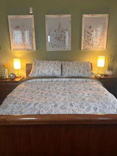 a bedroom with a bed with two lamps and two posters at Private Gated Garden Suite in Historic Home, walk to UNM Football and Basketball, UNM and Pres Hospitals in Albuquerque