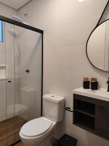 a white bathroom with a toilet and a mirror at Suíte privativa Vila Dom Pedro in Paraty