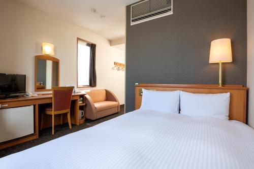 una habitación de hotel con una cama y un escritorio en Moriyama Art Hotel, en Moriyama