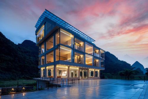 een gebouw met een zonsondergang op de achtergrond bij Yi Zhan Mountain Homestay in Xingping