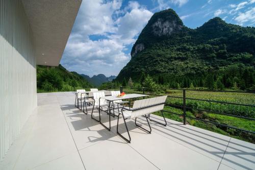 ein Balkon mit Tisch und Stühlen und Bergen in der Unterkunft Yi Zhan Mountain Homestay in Xingping