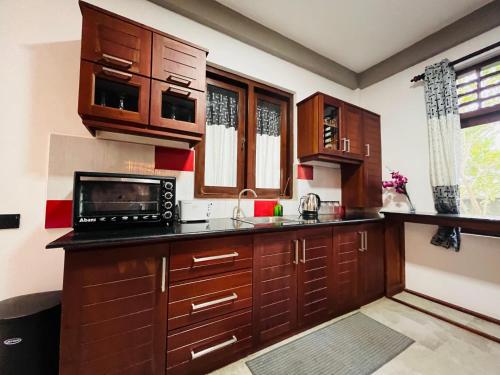 Una cocina con gabinetes de madera y microondas. en Hidden Gem - Private Villa, en Tangalle