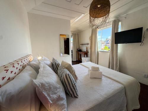 Una cama blanca grande en una habitación con ventana. en Vila Saruê, en Búzios