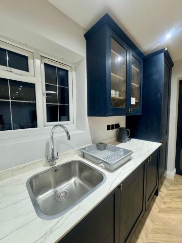 a kitchen with a sink and blue cabinets at Richard guest house in Roydon