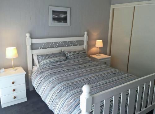 a white bed in a bedroom with two lamps at Eastgarth in Venus Bay
