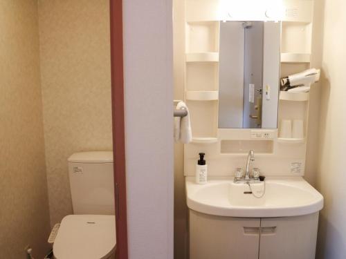 Un baño con inodoro, lavabo y espejo. en Moriyama Art Hotel, en Moriyama