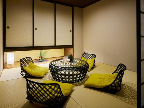 a dining room with a table and chairs with yellow pillows at Minn Kanazawa in Kanazawa