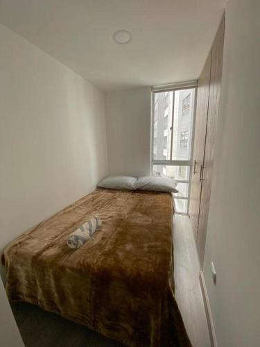 a large bed in a white room with a window at Apartamento en Manizales in Manizales