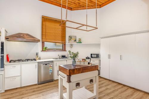 a kitchen with white cabinets and a wooden island at Bendigo Signature Accommodation on Barnard in Bendigo