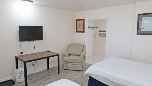 a bedroom with a bed and a chair and a television at Sawmill Lodges Motel in Hennessey