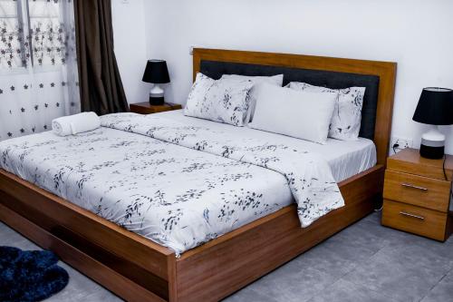 a bedroom with a large bed with a wooden frame at Kwanskrom Villa Biggies Homes in Winneba