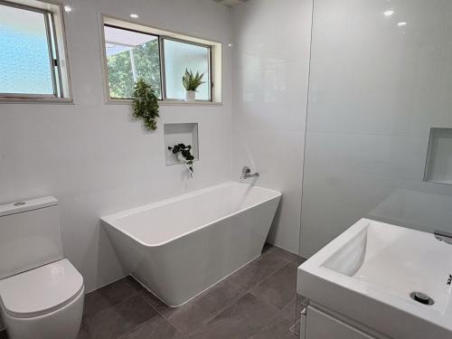 a bathroom with a tub and a toilet and a sink at Bright & Spacious Getaway - East Gosford in Point Frederick