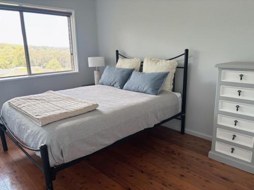a bedroom with a bed with a dresser and a window at Bright & Spacious Getaway - East Gosford in Point Frederick
