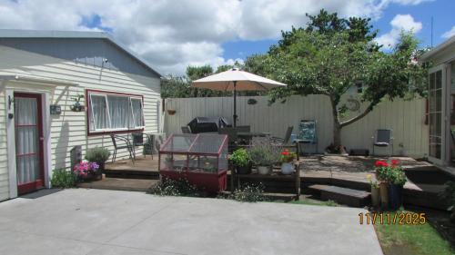 a patio with an umbrella and a house at Cozy Haven - Waihi in Waihi